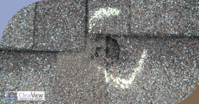 Close-up of severe hail damage on asphalt shingles with chalk marking