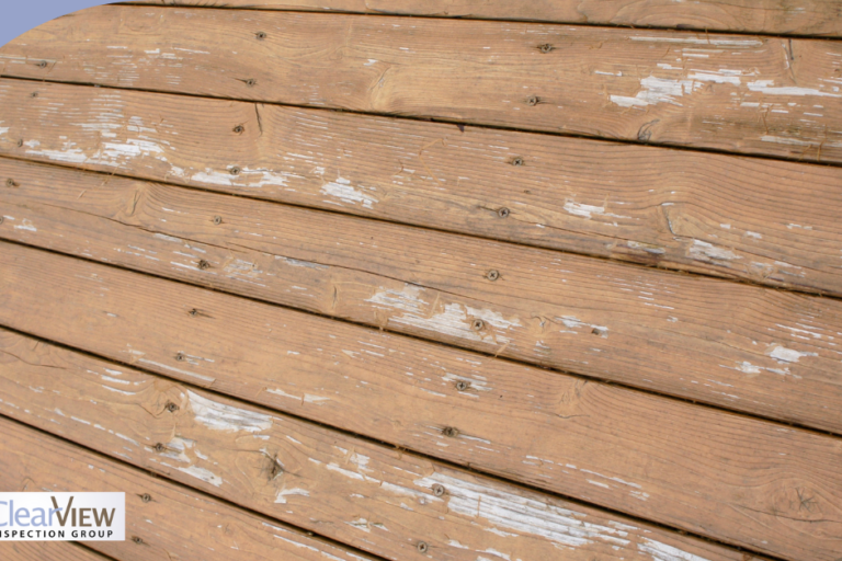 Weathered wooden deck boards with peeling paint and signs of aging.
